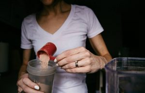 A person adding protein shake powder in a cup - Dato Darren Yaw